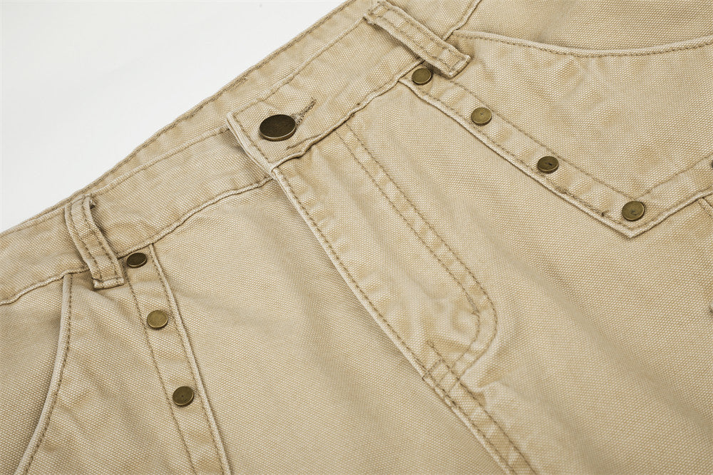 Close-up of beige cargo pants waistband and front panel with riveted pocket detail