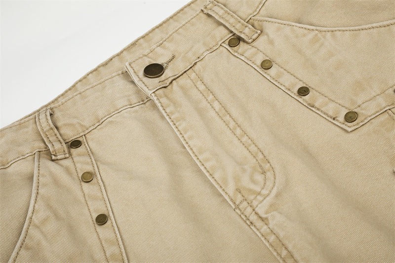 Close-up of beige cargo pants waistband and front panel with riveted pocket detail