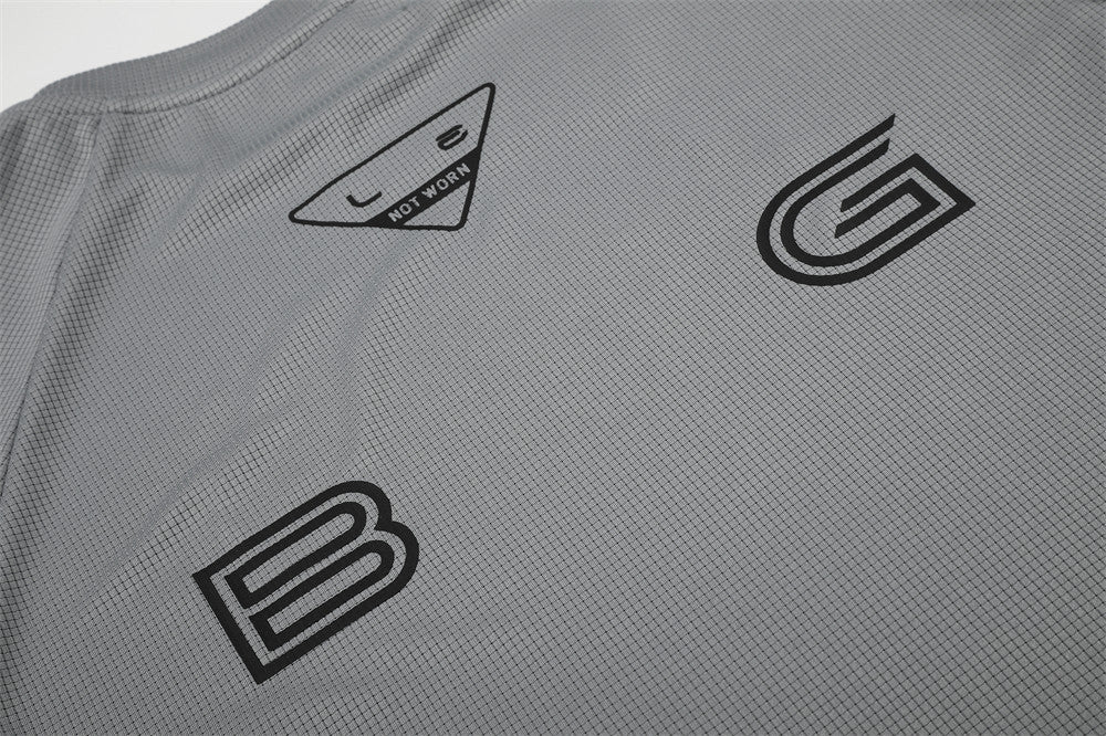 Close-up of gray shirt front with B and G logo prints and triangle neck label