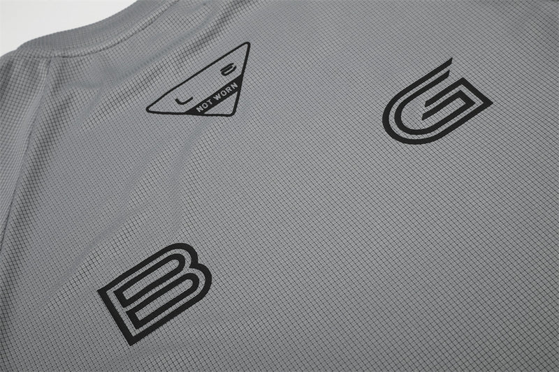 Close-up of gray shirt front with B and G logo prints and triangle neck label