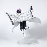 The Demon Slayer Shinobu Kocho Action Figure (15cm) showcases a dynamic pose with a butterfly-themed cape in white, black, and purple. Her black hair has a purple clip, and the figure stands on a clear base, simulating motion or flight.