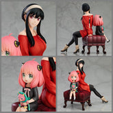 The Spy x Family Anya and Yor PVC Figure portrays an adorable mother-daughter moment, showcasing two figures sitting on a sofa. Yor, in a red dress and black boots with long dark hair, resembles her animated character, while the child with pink hair holding a toy captures Anya&