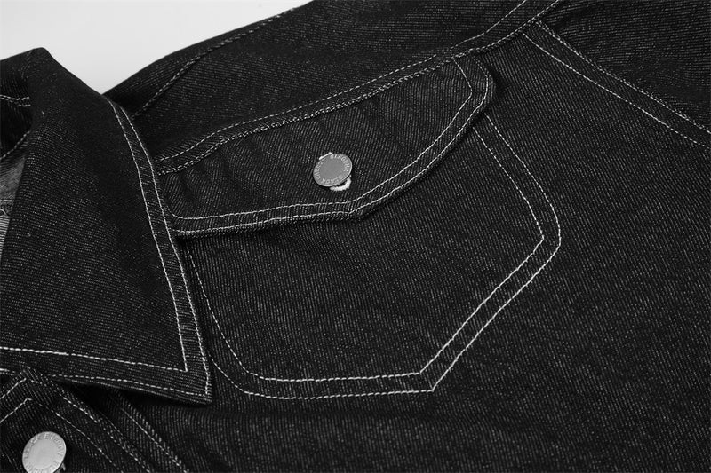 Close-up of black chest pocket and shoulder panel on denim jacket