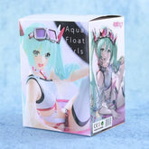 The product box features an anime-style PVC figure of Hatsune Miku with aqua hair, goggles, and a swimsuit. Labeled as "Hatsune Miku Swimsuit with Float Ring 11cm PVC Figure – Cute Summer Collectible," it includes detailed illustrations and product info.