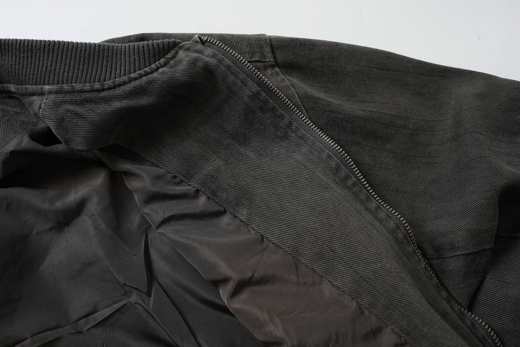 Veste bomber en jean délavé déconstruite à empiècement croisé et coutures effilochées