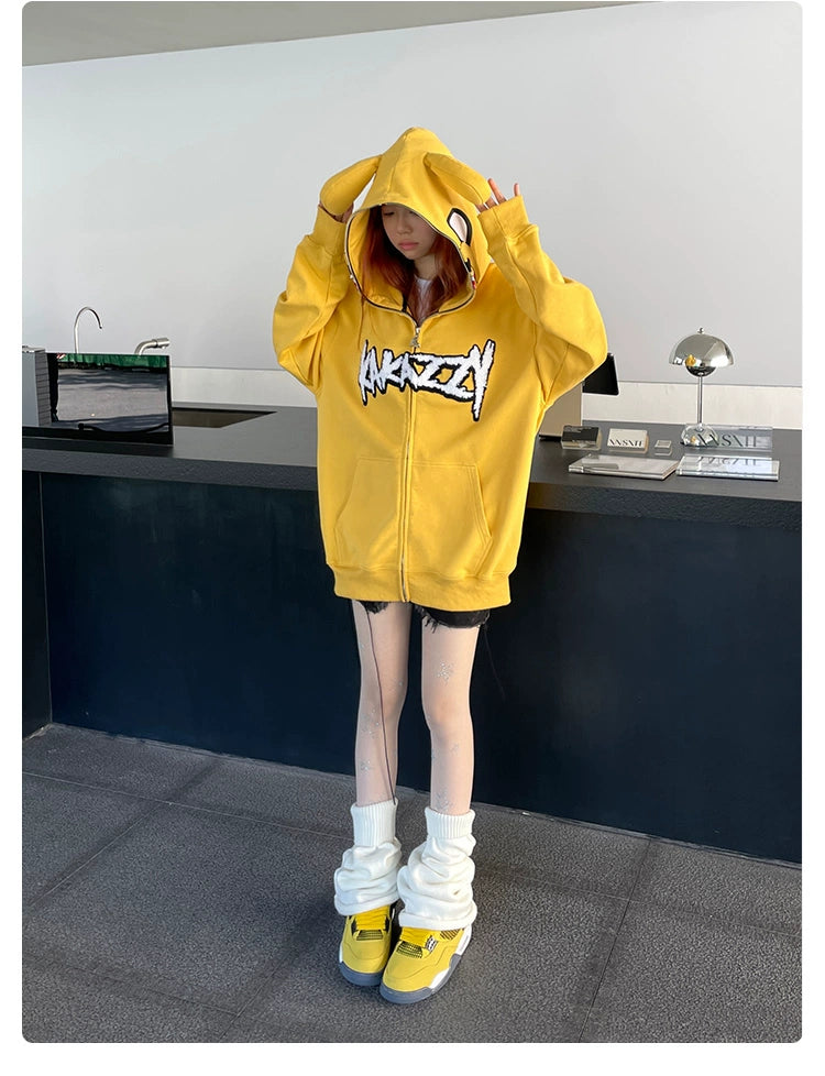 Indoors, a person models the Seakoff Kawaii Yellow Dog Hoodie—an oversized 400GSM cotton zip-up—exuding anime streetwear vibes. Paired with graphic white shorts, wrapped boots, and yellow sneakers, they&