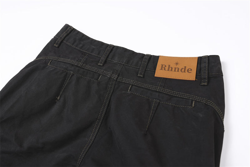Close-up of back waistband on black cargo pants with tan brand patch and belt loops