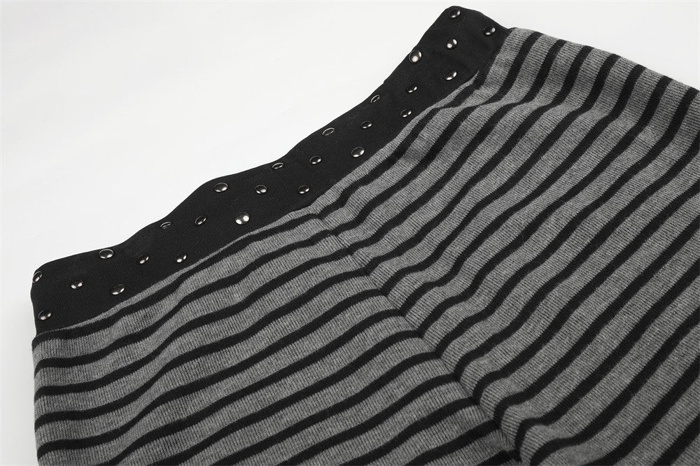 Waistband and upper leg of black and gray striped pants with studs, close-up view