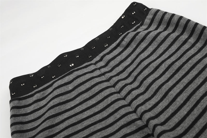 Waistband and upper leg of black and gray striped pants with studs, close-up view