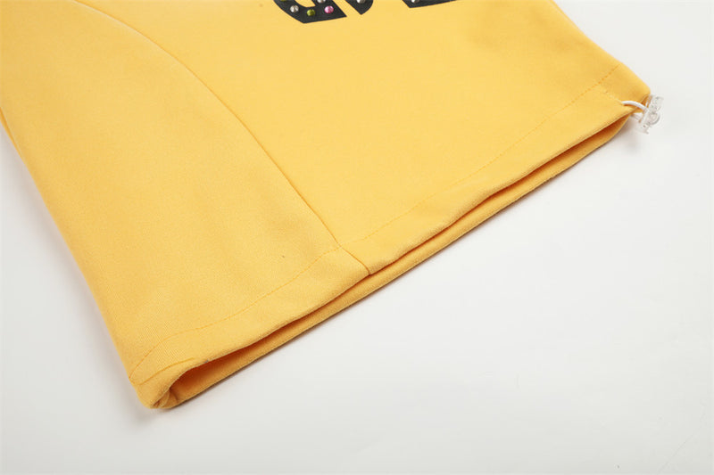 Close-up of yellow sweatpants hem with curved seam detail