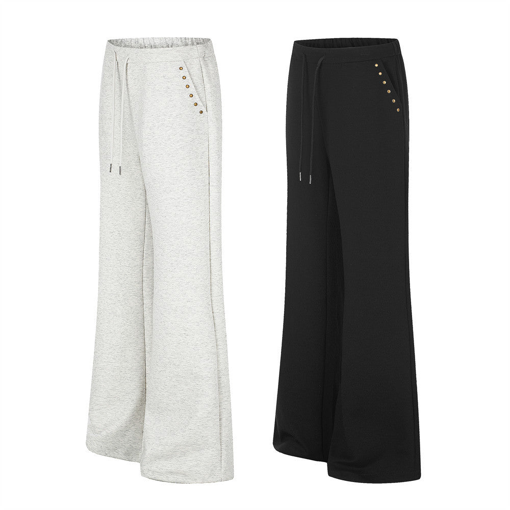 Wide leg sweatpants with gold stud detail and stud script graphic on lower leg, shown in black and light grey