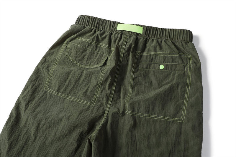 Close-up of the olive pants back showing two outlined pockets and a green snap closure