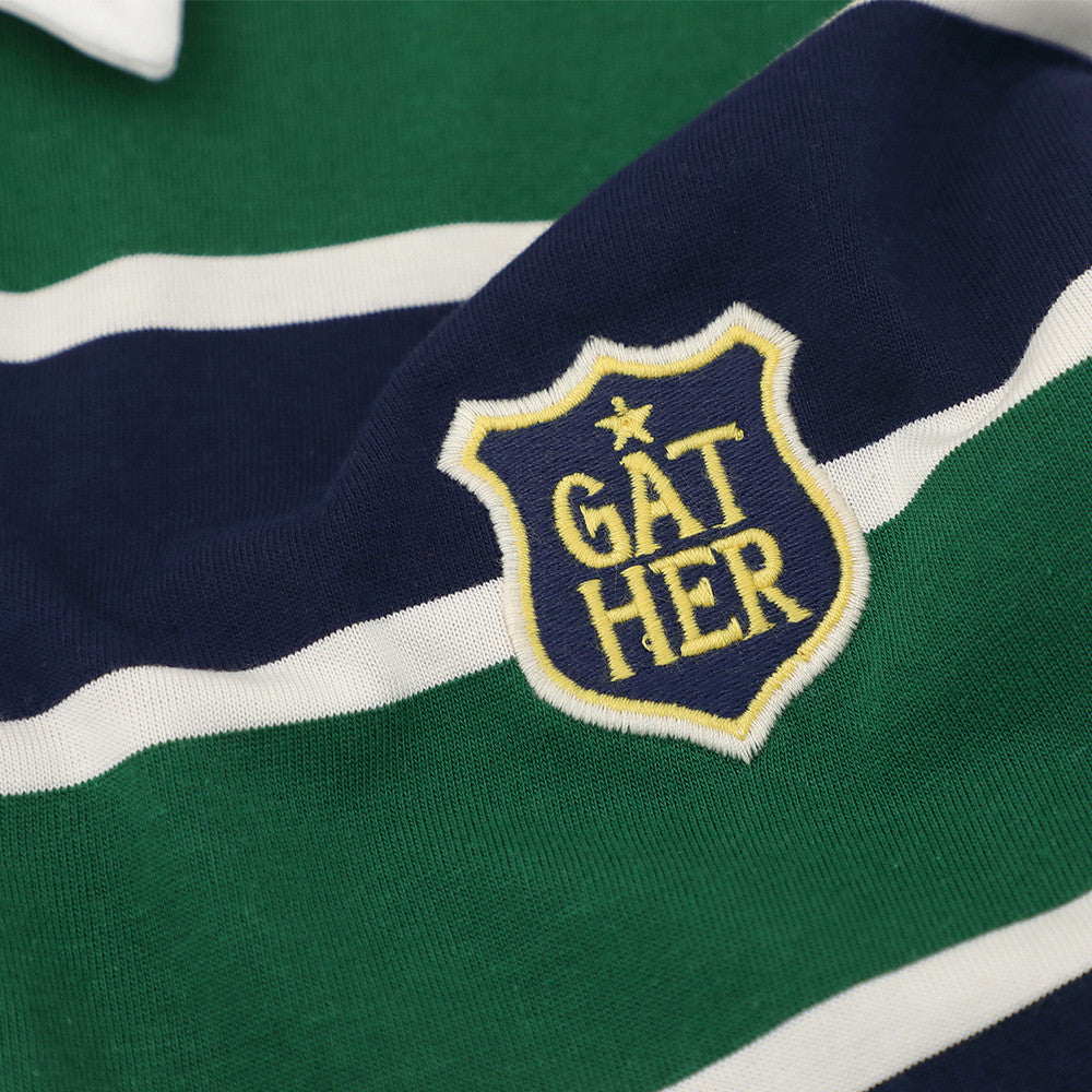 Close-up of embroidered crest patch on navy and green striped polo shirt