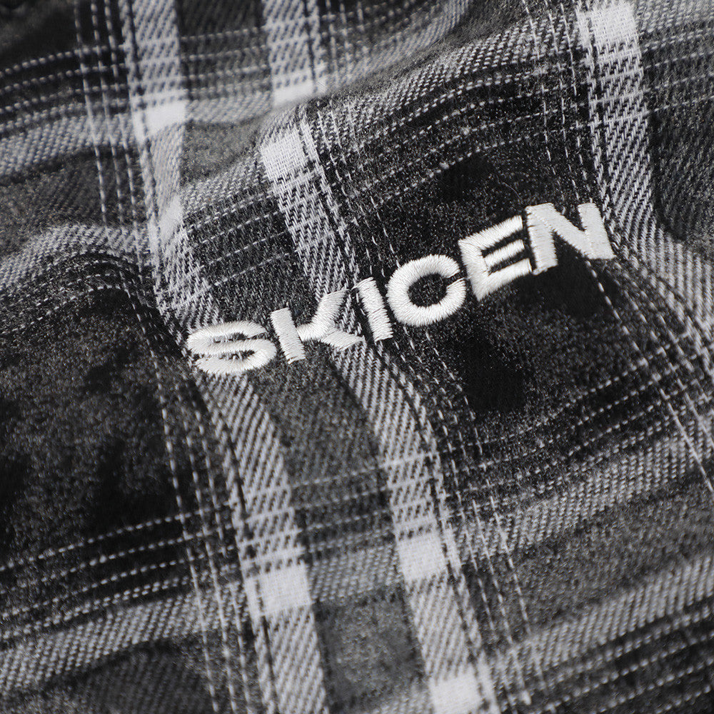 Close-up of black plaid flannel with embroidered SKICEN lettering