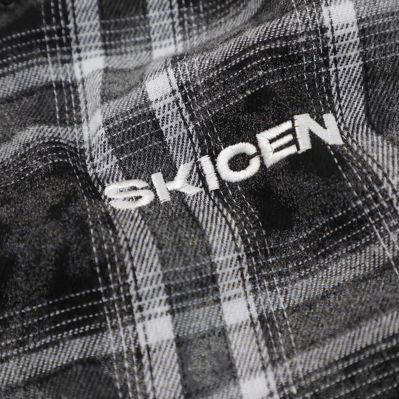 Close-up of black plaid flannel with embroidered SKICEN lettering
