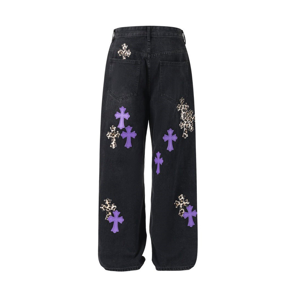 Black baggy jeans with purple and leopard cross patches, back flat lay