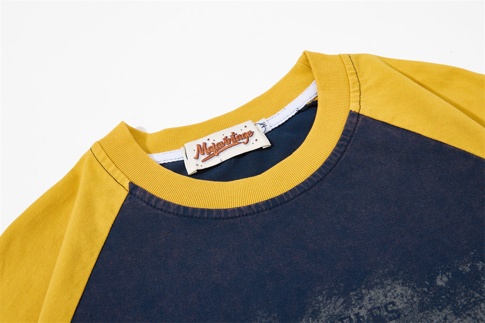 Close-up of a vintage colorblock raglan T-shirt with mustard yellow sleeves, navy body, and ribbed crew neckline