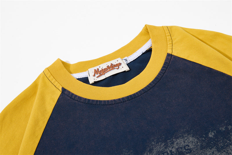 Close-up of a vintage colorblock raglan T-shirt with mustard yellow sleeves, navy body, and ribbed crew neckline