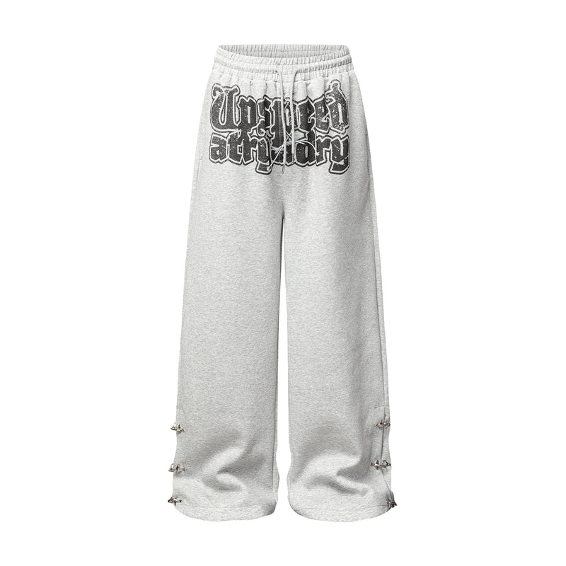 Pantalon de survêtement à jambes larges gris chiné avec imprimé graffiti effet usé et détails métalliques argentés en forme de pointes aux ouvertures des ourlets