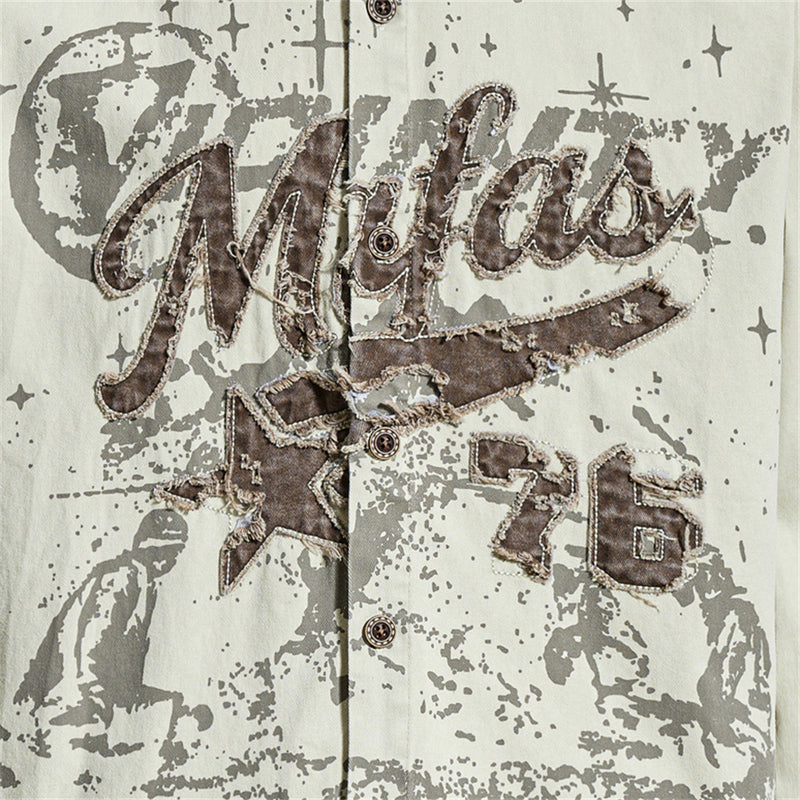 Close-up of front graphic on cream shirt with distressed brown appliqué lettering