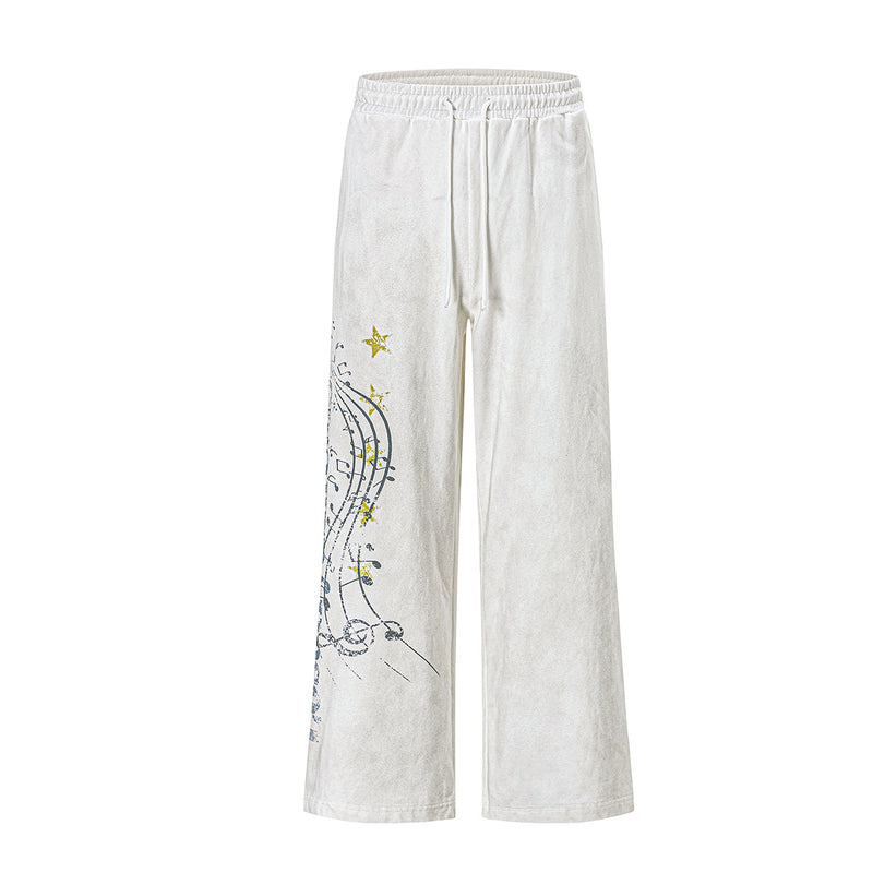 Pantalon de survêtement délavé à jambe large avec motif de notes de musique et d’étoile sur la jambe gauche, en blanc cassé et noir