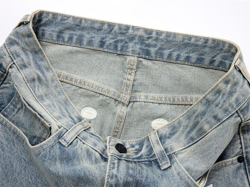 Close-up of denim waistband and button closure on light wash jeans