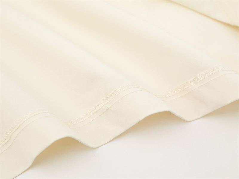 Cream shirt hem close-up with scalloped stitch detail along the edge