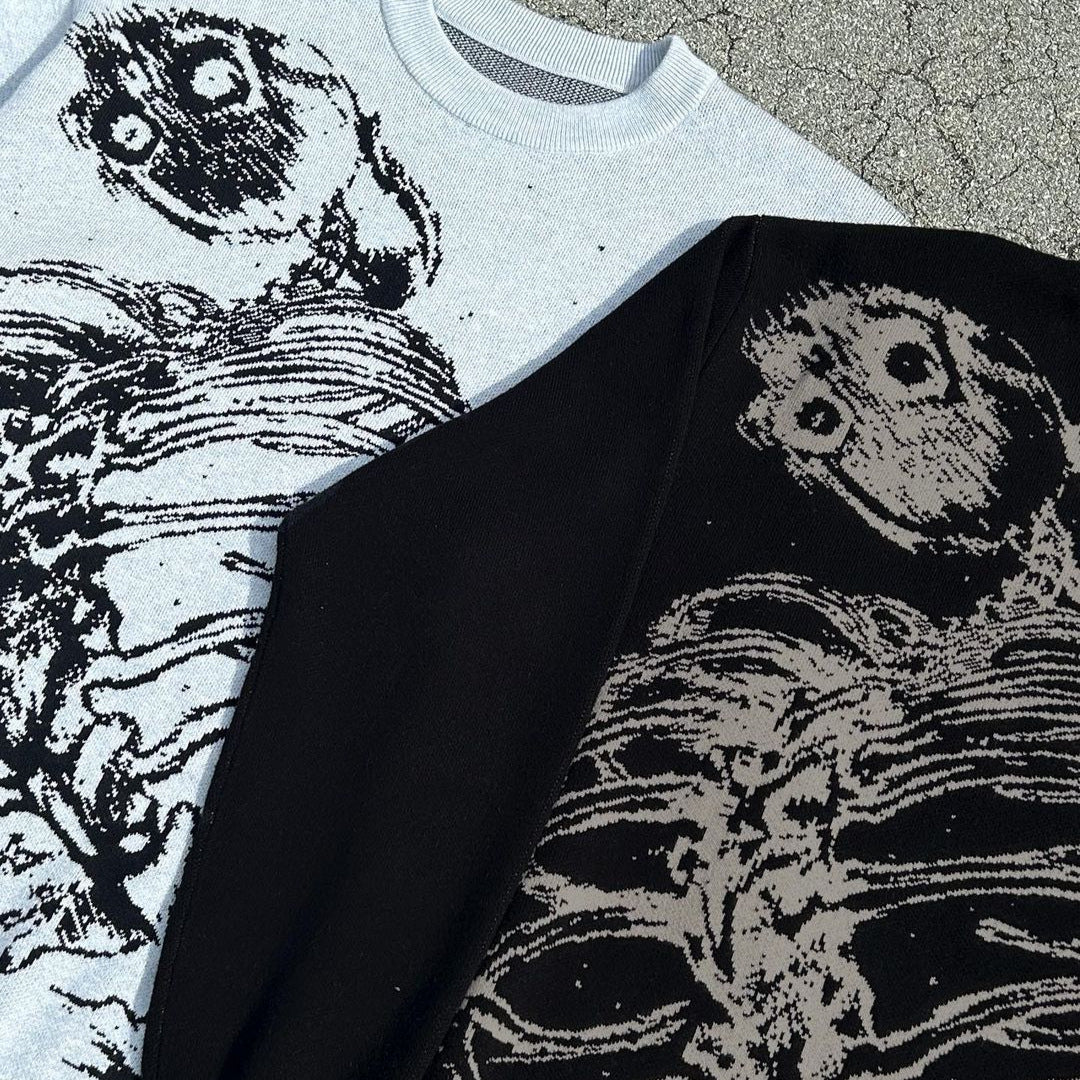 Displayed on a textured surface are two Seakoff Premium Skeleton Ribcage Knit Sweaters in gothic streetwear jacquard design. The left is white; the right is black. Both feature contrasting skeleton ribcage designs with large eyes, epitomizing alternative fashion.