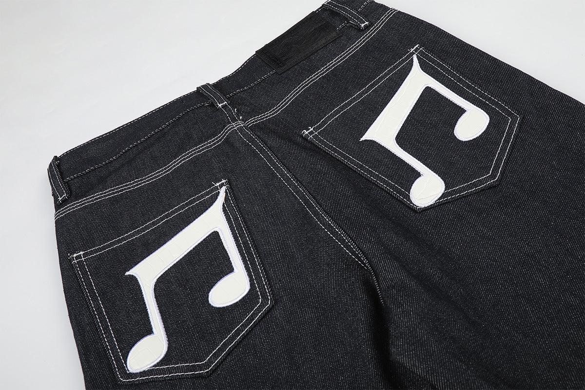 Jean baggy à jambes larges avec broderies et patch en cuir motif notes de musique — Denim noir brut