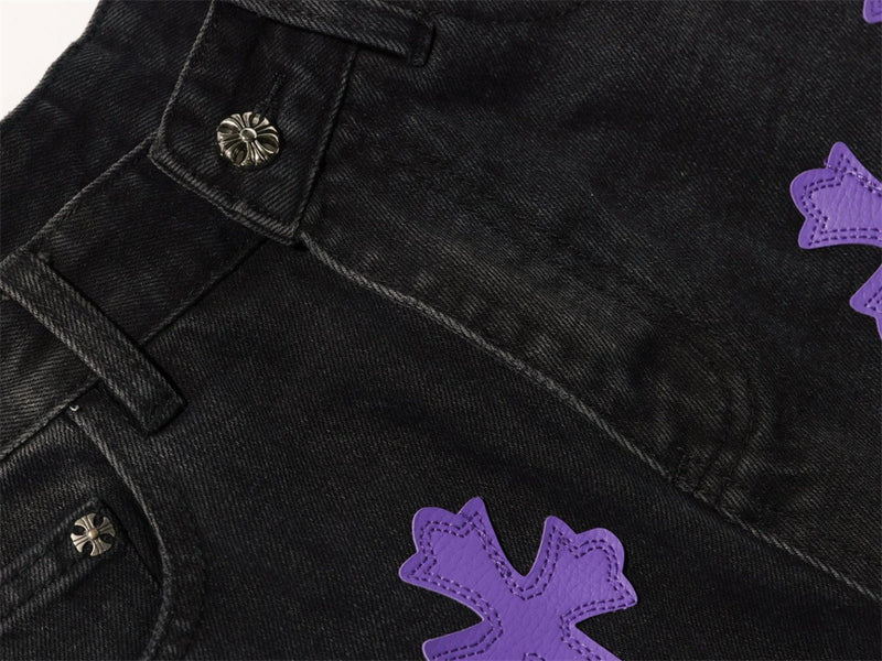 Close-up of black jeans front waistband and purple cross patch detail