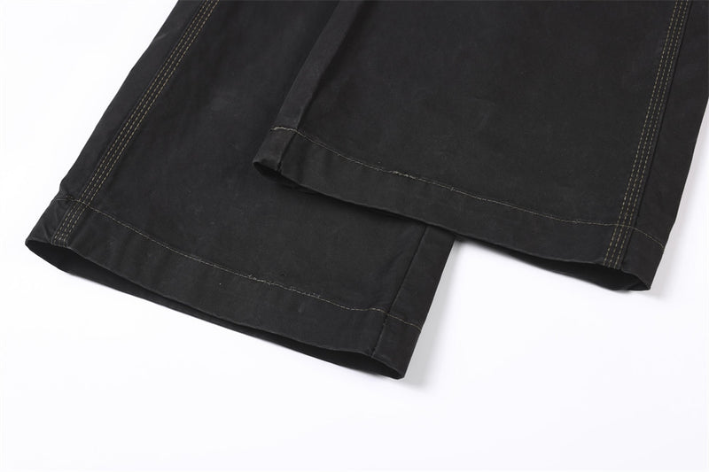 Close-up of wide black pant cuffs with straight hems and contrast stitching