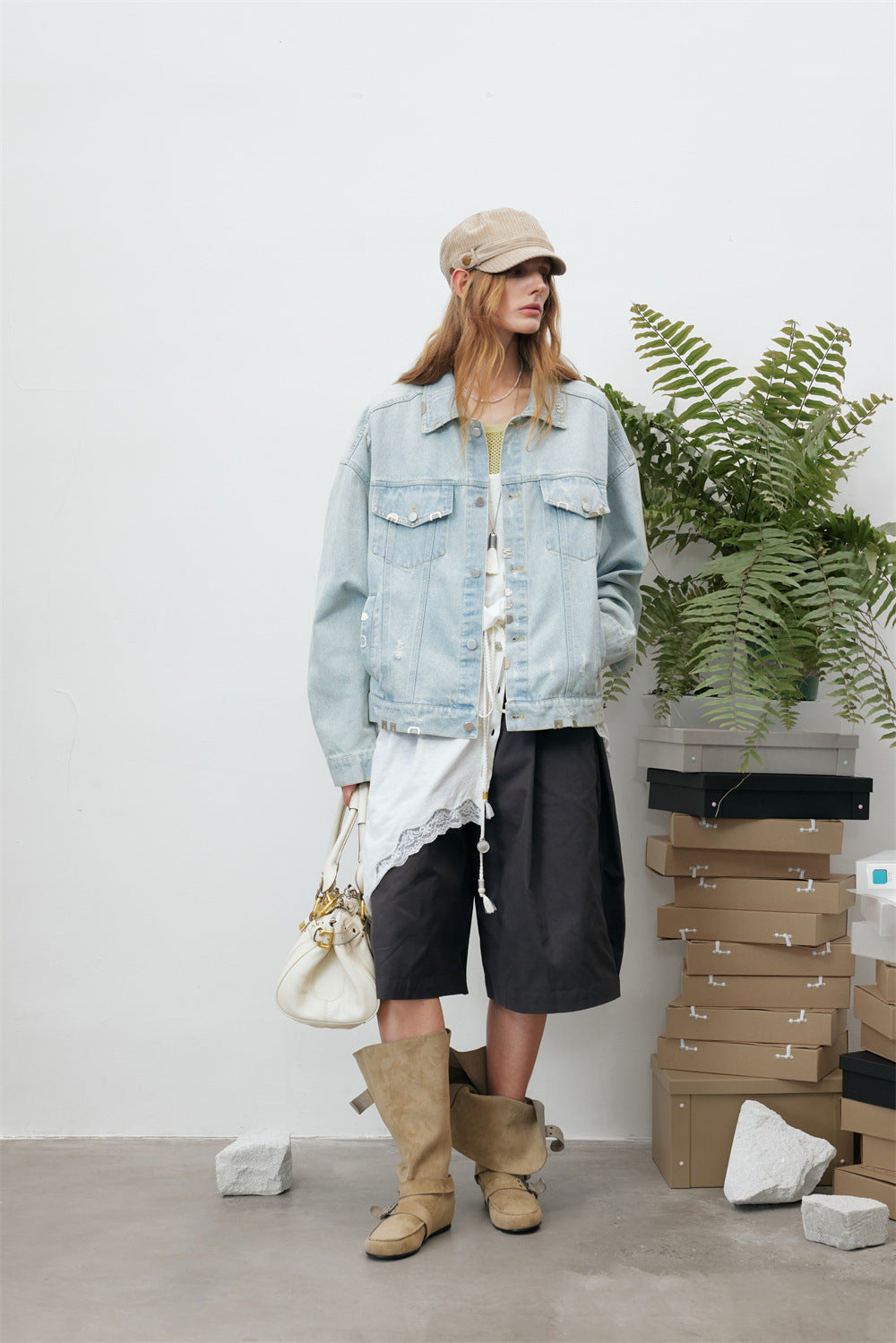 Front view of a model wearing a light wash denim jacket with flap chest pockets and frayed accents