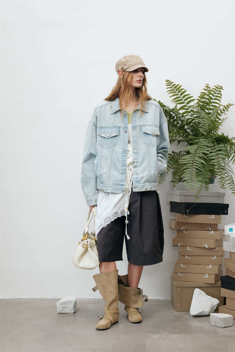 Front view of a model wearing a light wash denim jacket with flap chest pockets and frayed accents