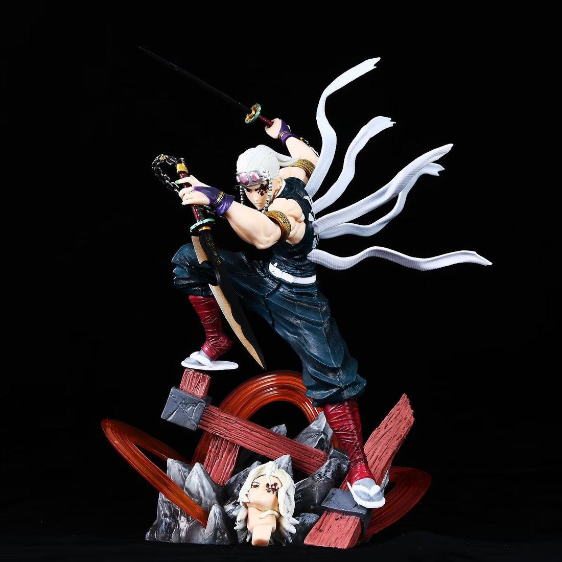 This high-quality PVC Tengen Uzui figure showcases the Sound Hashira with white hair and a headband, wielding dual swords in a dynamic pose atop wooden and rocky debris, accentuated by flowing ribbons against a solid black backdrop. Part of the Demon Slayer collection, it includes a double-headed eagle replacement.