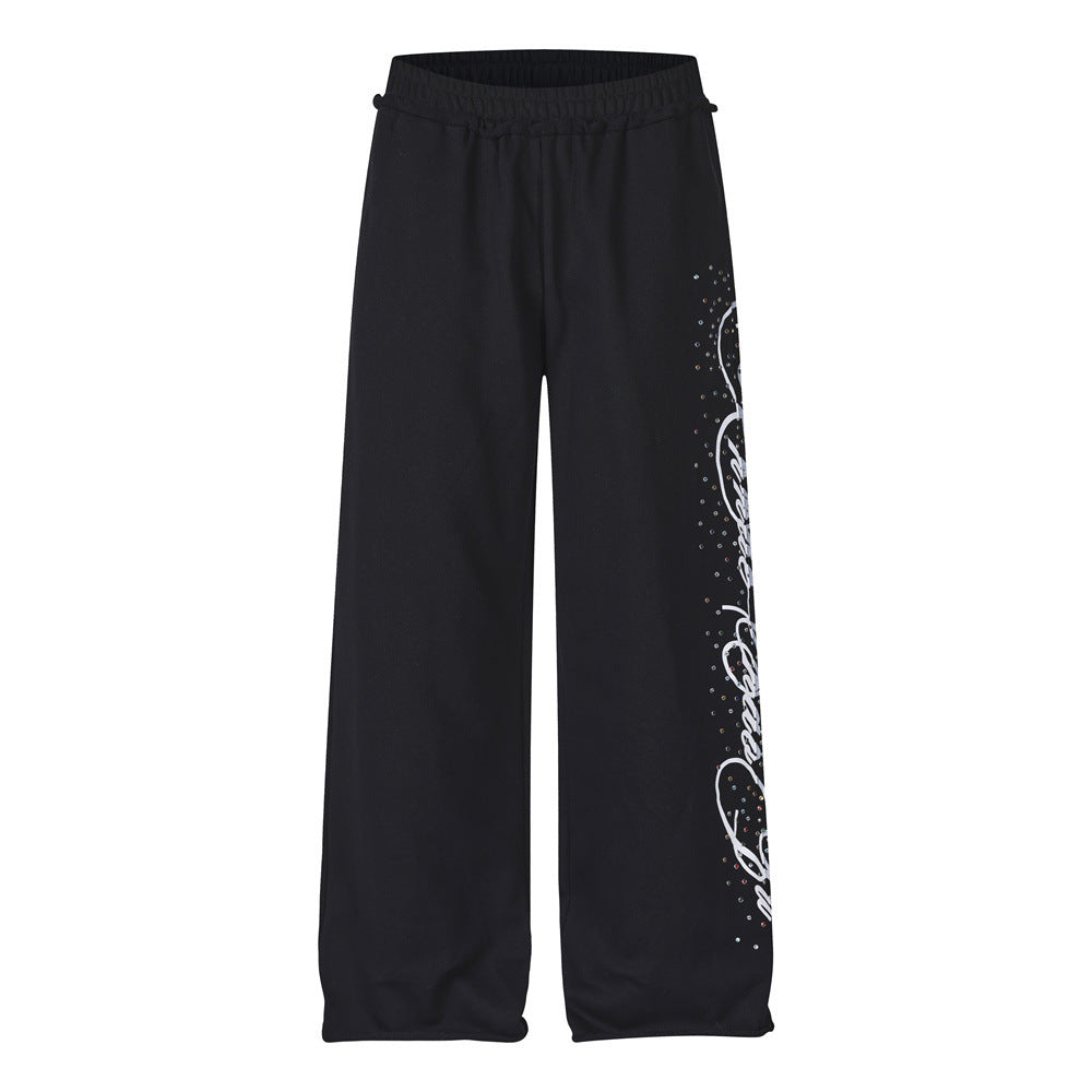 Men's black wide-leg sweatpants with rhinestone script graphic detail on the leg