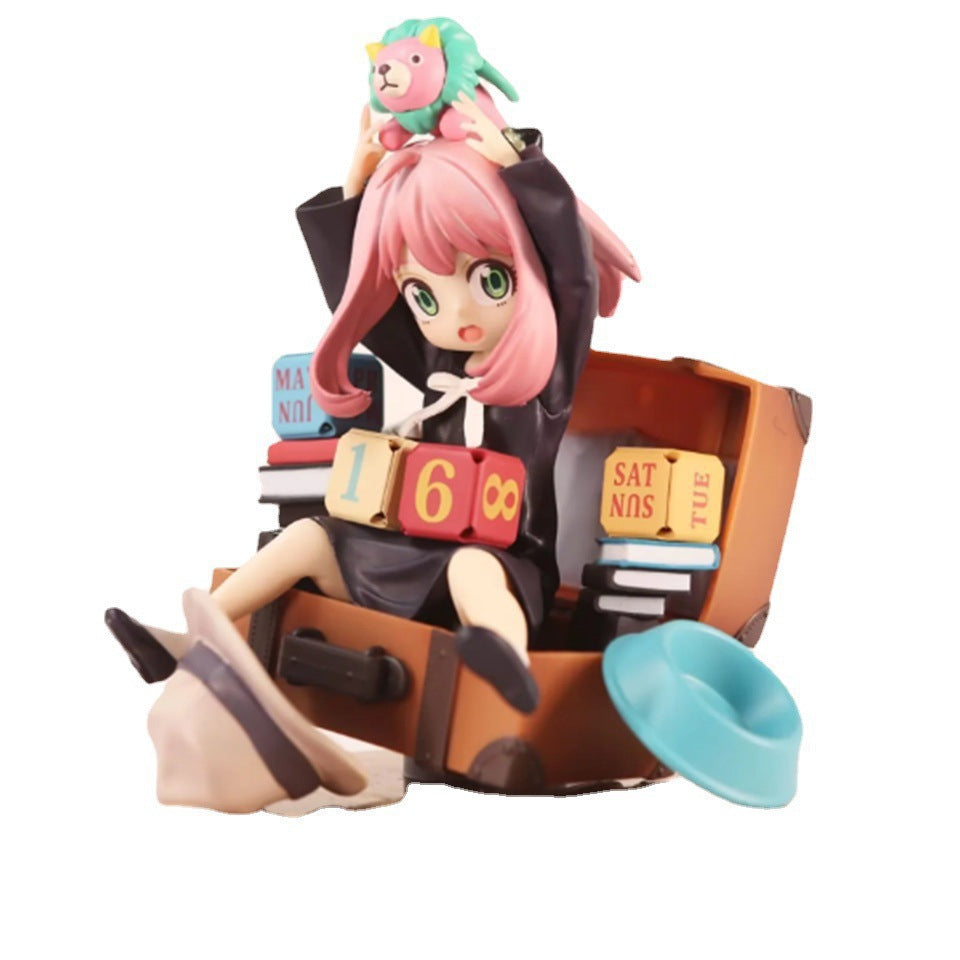 The Spy x Family Anya Forger PVC figure features a pink-haired anime character in a suitcase with a plush lion toy, colorful blocks, and day-labeled numbered blocks.