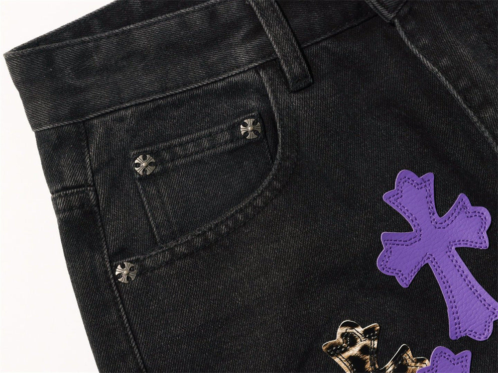 Close-up of black jeans front pocket with purple cross patch and metal rivets