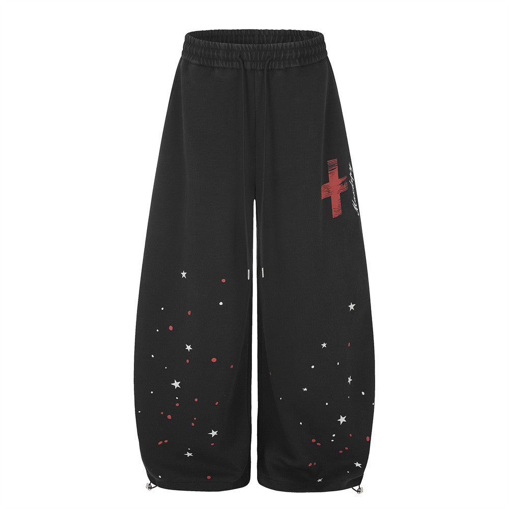 Schwarze Oversized Wide-Leg-Sweatpants mit rotem Kreuzmotiv und weißem Sternprint am unteren Bein, Vorder- und Rückansicht