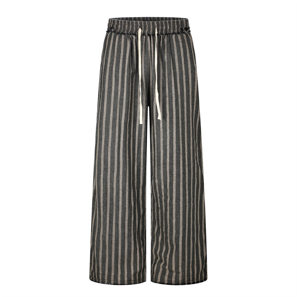 Men's wide-leg vertical striped drawstring pants in charcoal and natural linen tones with raw-hem distressed detailing, front