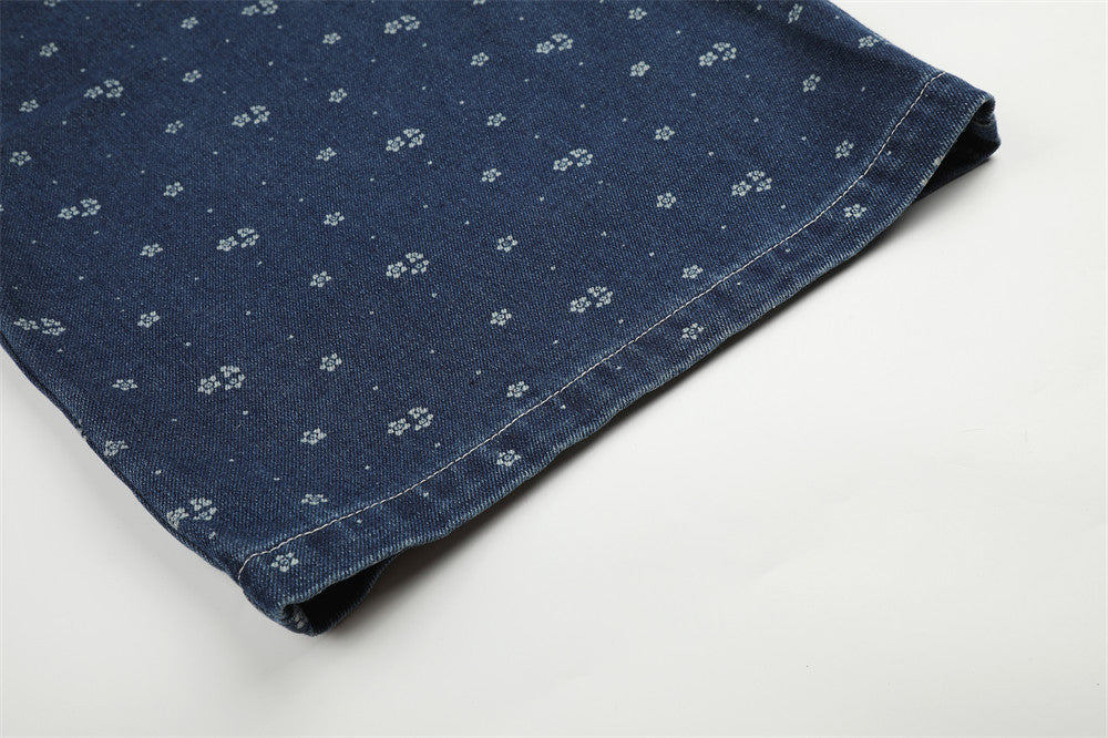 Close-up of hemmed dark blue denim leg with small floral print