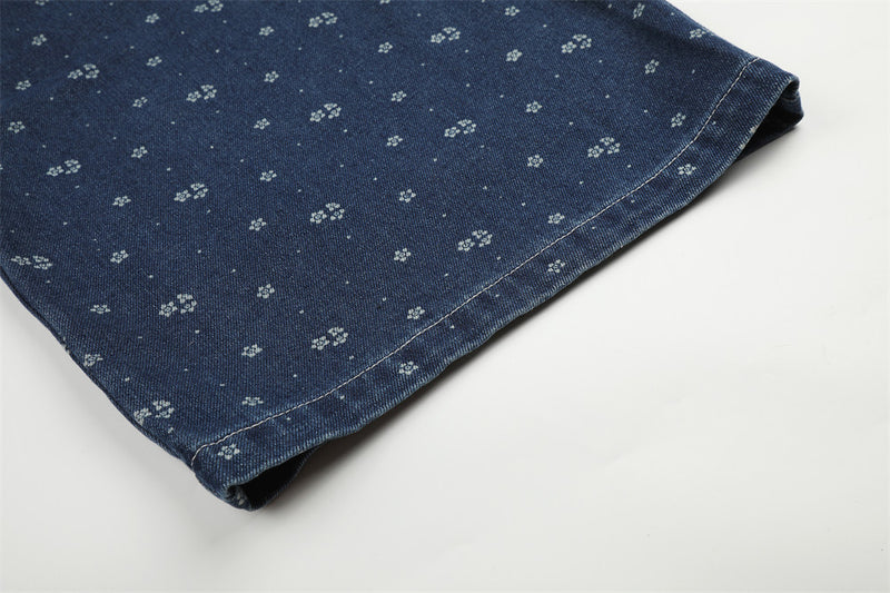 Close-up of hemmed dark blue denim leg with small floral print