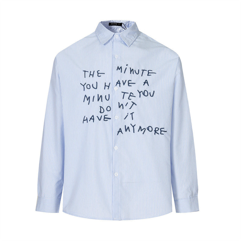 Front view of a light blue striped long sleeve shirt with dark embroidered letter graphic