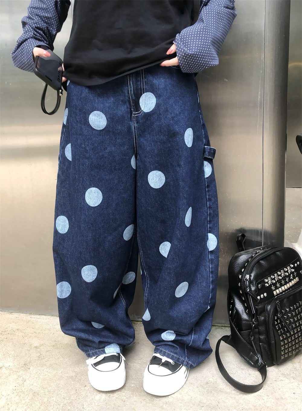 Oversized wide-leg dark navy jeans with large light-wash polka dot print and carpenter side hardware detail