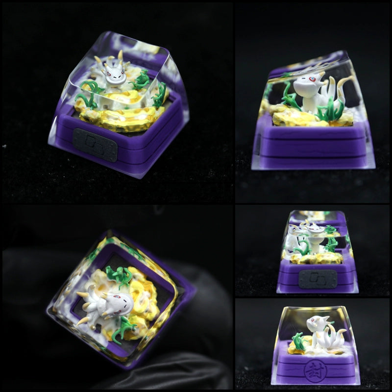 Part of the Naruto Bijuu collection, the Tailed Beasts Keycap showcases a small white creature with a horn amidst yellow flowers and greenery. It features a clear top and purple base, beautifully displayed from various angles against a black background.