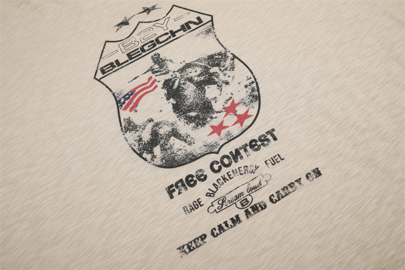 Close-up of beige tee front graphic and printed text below the badge design