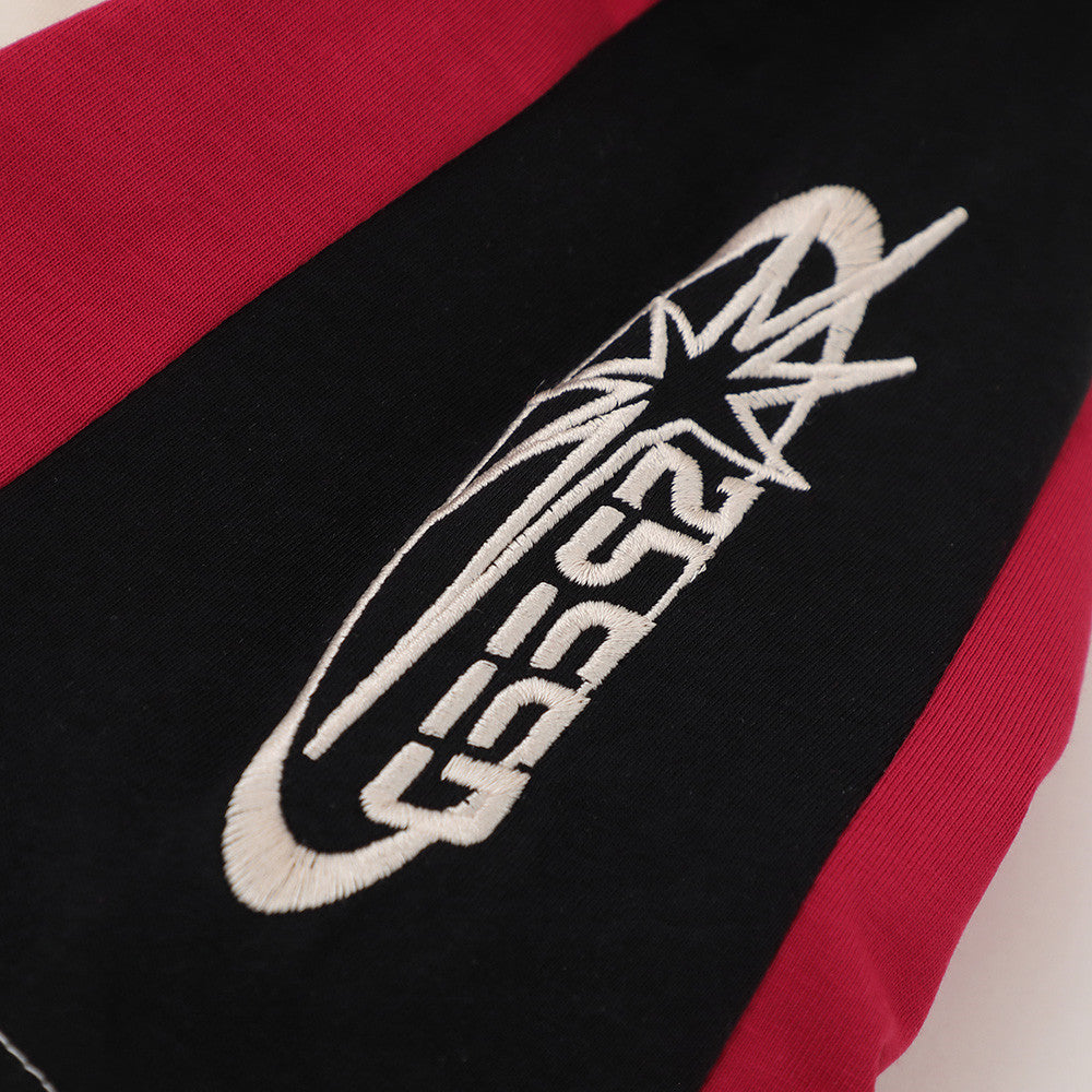 Close-up of embroidered logo on black sleeve panel with red side trim