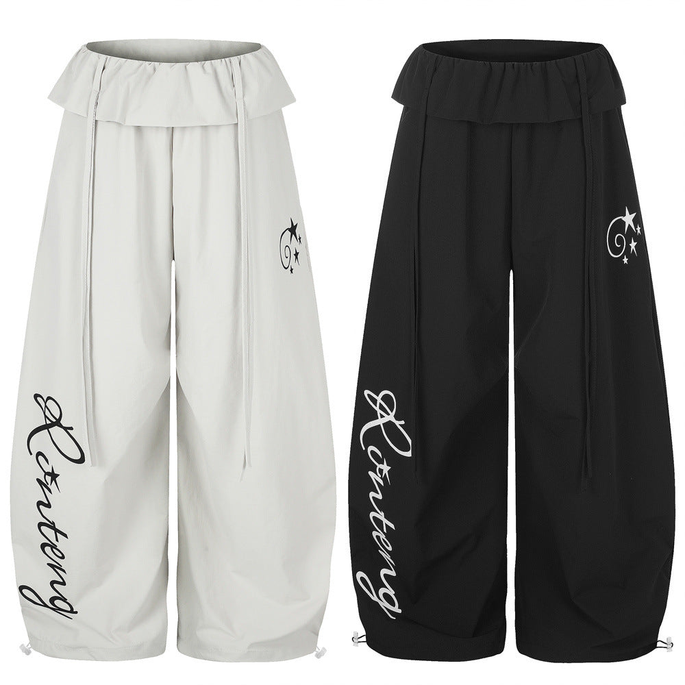 Wide-leg balloon pants with cursive letter print and star graphic in black, featuring fold-over elastic waistband and drawstr
