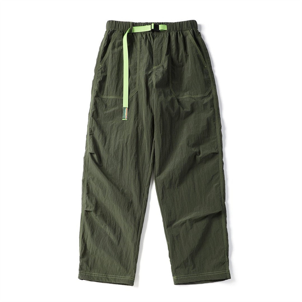 Front view of olive green parachute pants with a bright green drawcord, belt, and cargo pockets