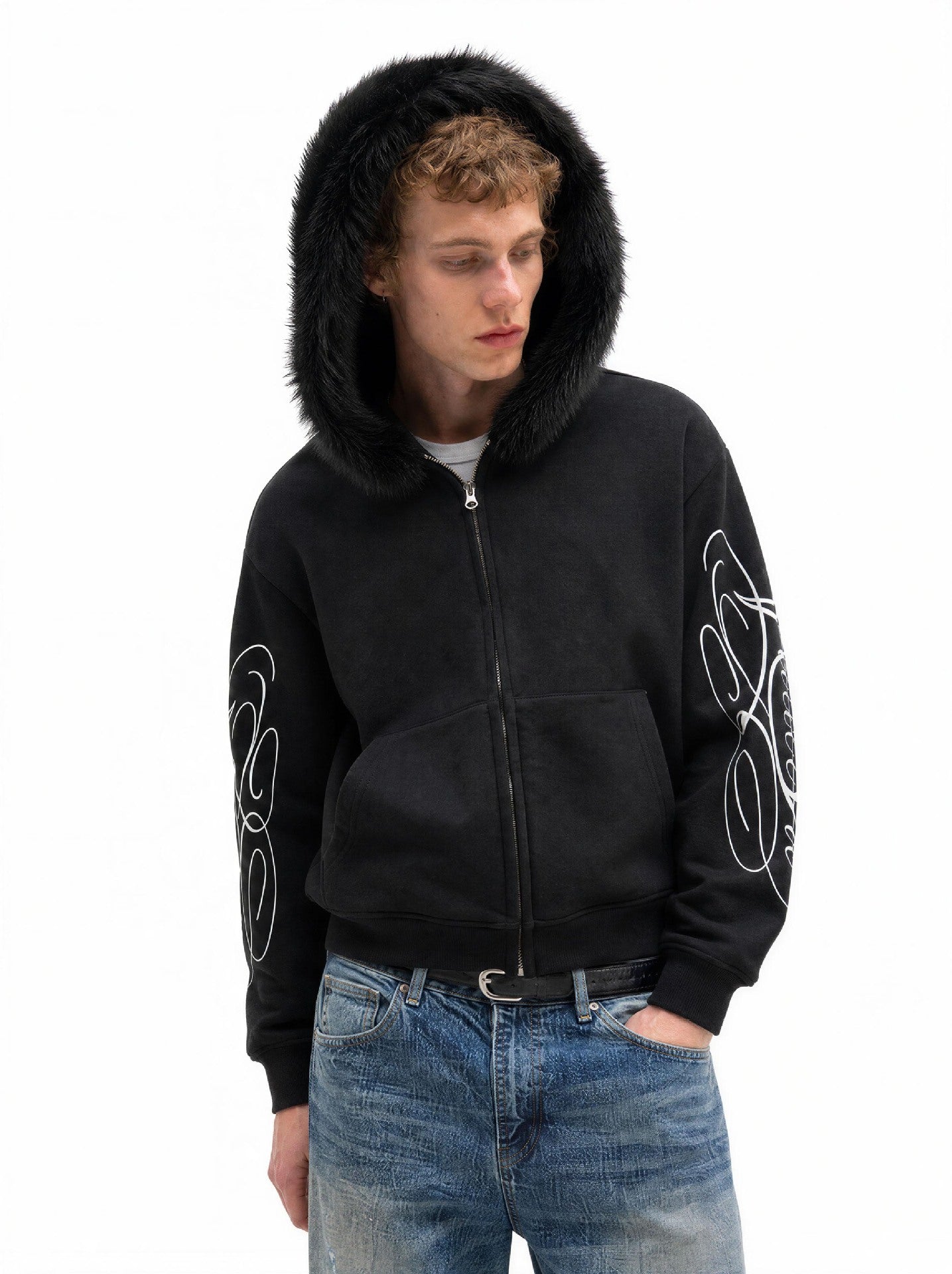 Sweat à capuche oversize zippé avec bordure en fausse fourrure et inscription manuscrite sur la manche, noir, porté avec un jean effet usé