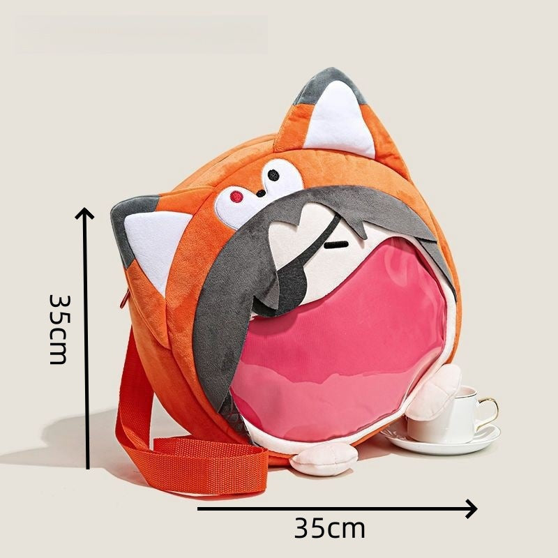 The Seakoff Adorable Fox Plush Shoulder Bag features a cute fox design with ears, eyes, and nose, an open main compartment revealing a pink interior. This high-quality plush bag is 35cm by 35cm and includes a transparent mouth pocket. A teacup sits beside it.